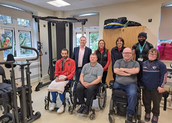 Group of people in wheelchairs sit in accessible gym.