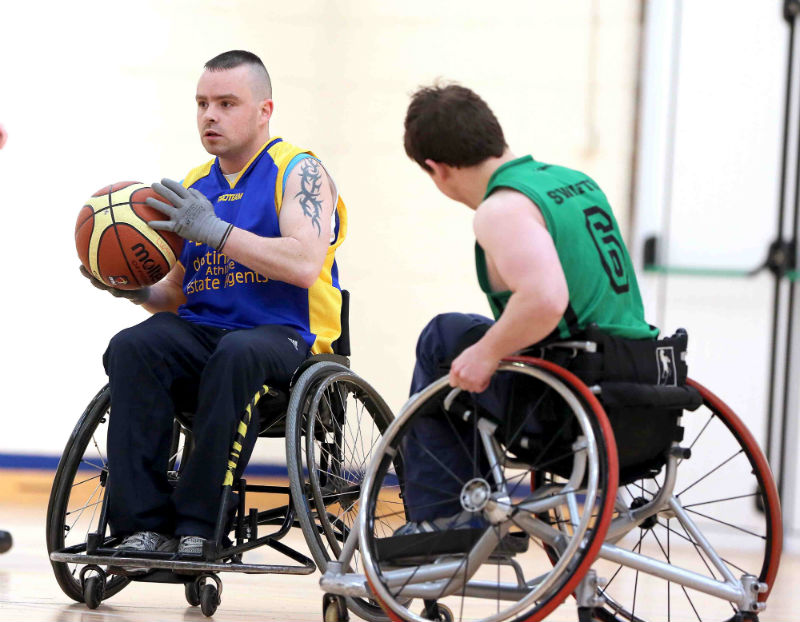 Two men in wheelchairs play basketball.