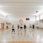 People playing volleyball in a gymnasium.