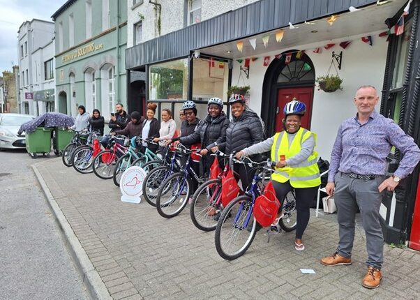 Group pose for picture while sitting on bicycles in a row.