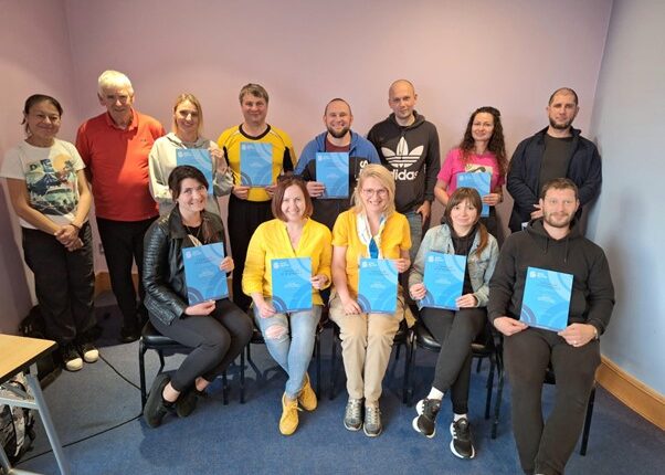 Group photo of people holding blue certificates.